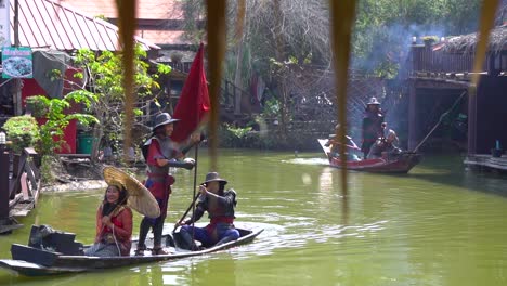 Slow-Motion-of-Performers-in-Traditional-Thai-Costumes-Sailing-in-Boats-in-Open-Museum-in-Erawan-National-Park,-Thailand