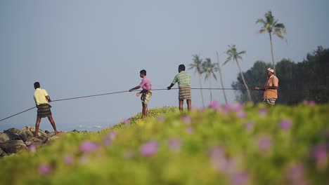 Local-fishermen-pulling-a-traditional-fishing-net,-Kappil-Beach,-Varkala,-India