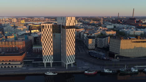 Aerial-view-of-the-Clarion-Hotel,-on-a-sunny-morning,-during-sunrise,-in-Jatkasaari,-Helsinki,-Finland---pull-back,-drone-shot