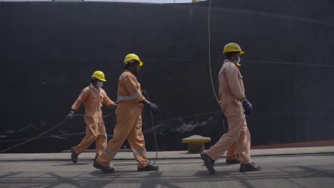 Dockworkers-Walking-At-The-Platform-While-Holding-Mooring-Line-Of-An-Anchored-Vessel-At-The-Port-Of-Paradip-In-India