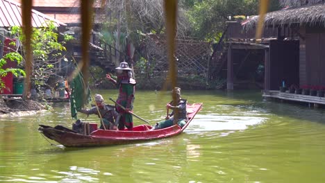 Slowmotion-of-Traditional-Thai-Boat-With-Men-in-Authentic-Warriors-Costumes-Sailing-in-Pond-of-Ancient-Siam-Open-Museum,-Erawan-National-Park,-Bangkok,-Thailand