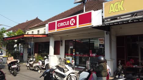 Circle-K-Convenience-Store-Shop-in-Indonesia,-Establishing-Shot-Street-Parking-and-People-around-Mini-Market-Facade-during-Daylight