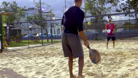Ein-Mann-Gibt-Beim-Beach-Tennis-Einen-Unterhandaufschlag
