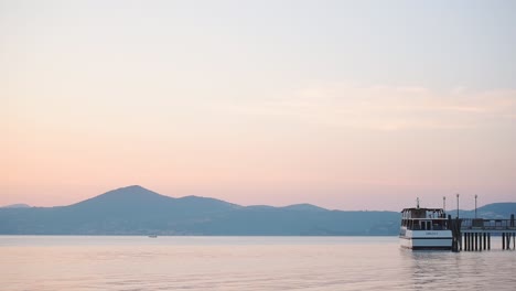 Panoramic-landscape-view-of-a-moored-boat-on-Lake-Bracciano,-Italy,-at-sunset