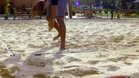 Bei-Einem-Beachtennisspiel-Wird-Ein-Ball-Aus-Dem-Sand-Aufgesammelt