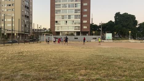 Group-of-children-playing-football-on-a-dirt-pitch