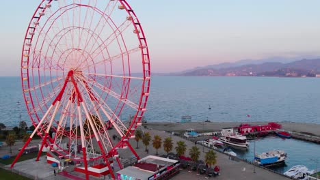 Aerial,-orbit,-drone-shot,-around-the-Ferris-wheel,-on-the-coast-of-the-Black-sea,-during-sunset,-in-Batumi-city,-Adjara,-Georgia