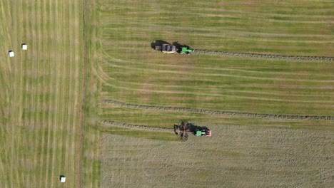 Top-view-drone-shot-of-two-tractors-working-with-hay-in-Rhenen-in-The-Netherlands