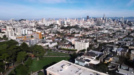 Drone-footage-presents-a-serene-view-of-San-Francisco's-Seven-Painted-Ladies,-iconic-Victorian-houses,-set-against-the-vibrant-cityscape-and-lush-greenery-of-Alamo-Square-Park