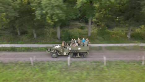 Parallel-drone-shot-of-an-American-Second-World-War-halftrack-driving-on-the-Ginkel-Heath,-in-commemoration-of-Operation-Market-Garden