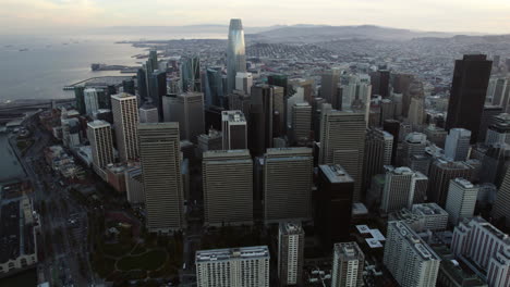 Flying-in-front-of-highrise-in-downtown-San-Francisco,-cloudy-sunrise-in-CA,-USA---Aerial-view