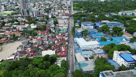 Aerial-forward-shot-of-bustling-highway-with-buildings-and-homes-in-middle-of-West-Crame,-San-Juan-City,-Philippines