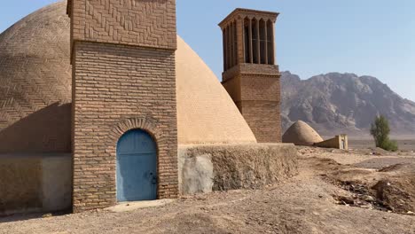 Water-reservoir-in-desert-region-the-brick-building-with-clay-dome-in-Iran-desert-area-mountain-landscape-in-background-in-a-clean-blue-sky-weather-in-summer-in-Yazd-windcatcher-to-fresh-ventilation