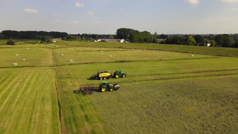 Rotating-drone-shot-of-two-tractors-working-with-hay-in-Rhenen,-The-Netherlands