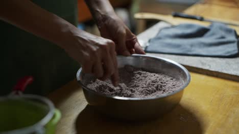 Mixture-of-chocolate-powder-and-white-flower-being-stirred-with-spoon-in-bowl-on-kitchen-counter,-filmed-as-close-up-slow-motion-shot