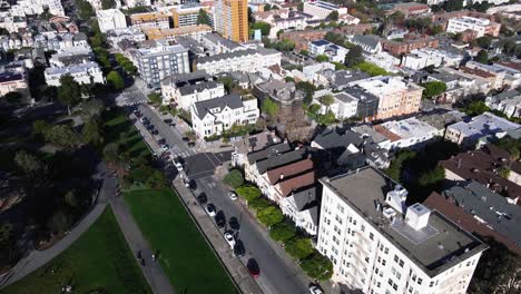 Drone-footage-presents-a-serene-view-of-San-Francisco's-Seven-Painted-Ladies,-iconic-Victorian-houses,-set-against-the-vibrant-cityscape-and-lush-greenery-of-Alamo-Square-Park