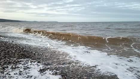 Sandy-waves-slow-motion-crash-onto-Anglesey-pebble-beach