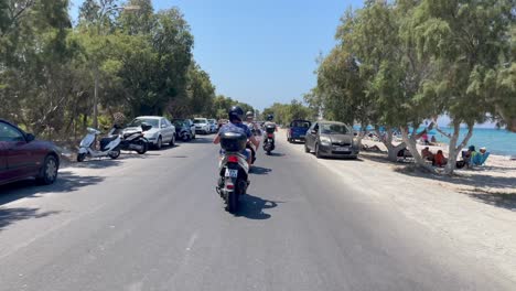 Tourists-riding-scooters-in-Kos-Island-village-beach-street
