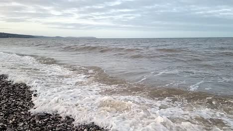 Sandy-waves-slow-motion-crash-onto-Irish-pebble-beach