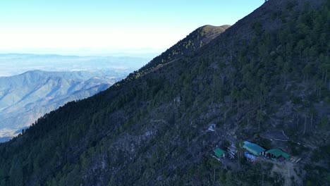 Drohnenansicht-In-Guatemala,-Die-über-Einen-Von-Grünen-Bäumen-Bedeckten-Vulkanberg-Und-Einen-Campingplatz-Auf-Einem-Hügel-Fliegt