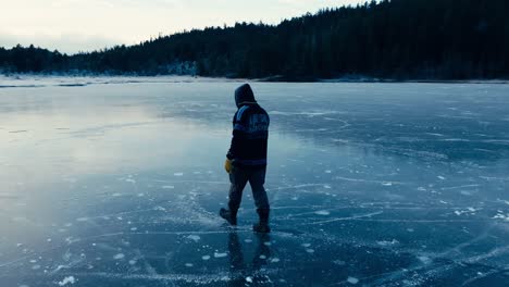 Indre-Fosen,-Trondelag-County,-Norway---A-Man-Strolling-on-the-Frozen-Surface-of-Omundvatnet-as-Dusk-Settles-in---Tracking-Shot