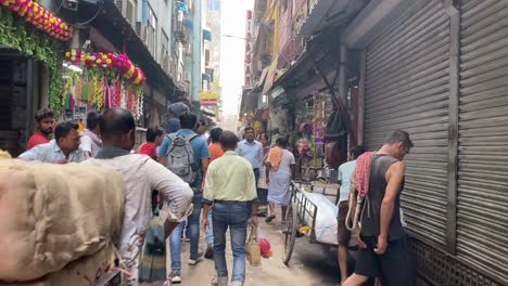POV-shot-of-locals-walking-around-busy-crowded-narrow-alley-in-Kolkata,-India-with-row-of-shops-on-both-sides-at-daytime