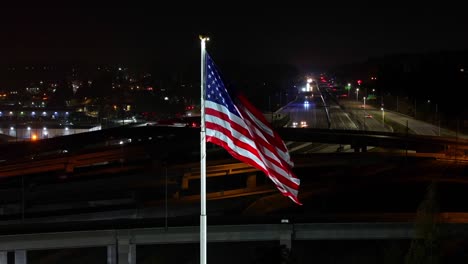Flagge-Der-Vereinigten-Staaten-Von-Amerika-Mit-Autobahn-Im-Hintergrund-Bei-Nacht