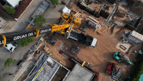 Aerial-view-looking-down-construction-crane-installing-smart-housing-module-on-construction-site-foundation