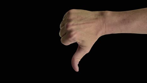 Close-up-shot-of-a-male-hand-giving-a-classic-thumbs-down-sign,-against-a-plain-black-background