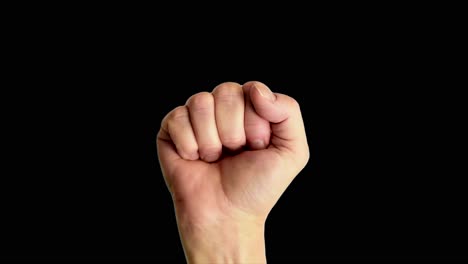 Close-up-shot-of-a-male-hand-holding-up-a-classic-power-or-fist-sign,-against-a-plain-black-background