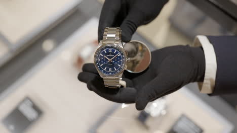 Behandschuhte-Händlerhände-Zeigen-Luxuriöse,-Modische-Boutique-Armbanduhr-über-Der-Glastheke