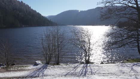 Wide-shot-of-the-snowy-Longemer-lake-and-surrounding-mountain-forest-in-Vosges,-France