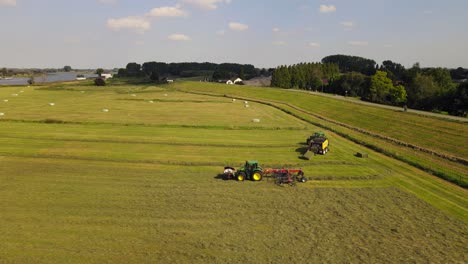 Parallel-drone-shot-of-two-tractors-working-hay-in-the-Netherlands