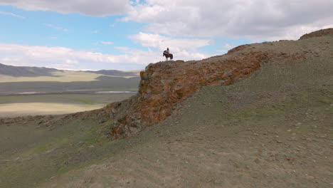 View-Of-An-Eagle-Hunter-Riding-The-Horse-In-Western,-Mongolia---Drone-Shot