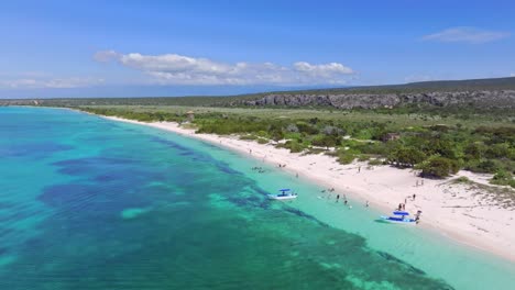Aerial-view-showing-tourist-with-boat-at-bay-of-las-Aguilas-in-pedernales,-beautiful-landscape-with-blue-water-and-and-sandy-beach