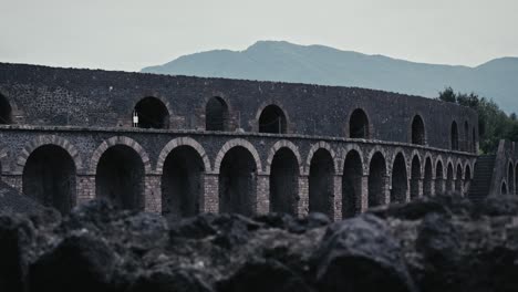 Ancient-amphitheater-of-Pompeii-against-hills,-Italy