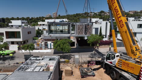 Smart-modular-housing-project-aerial-view-crane-lifting-unit-over-construction-site