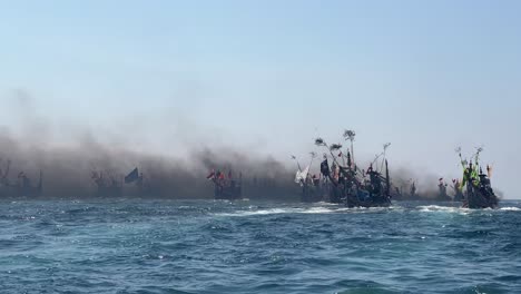 Fishing-boats-in-Indian-Ocean-during-Patik-Laut-festival-in-Muncar,-Banyuwangi,-Jawa,-Indonesia-covered-in-smoke-exhaust