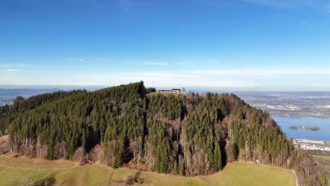 Aerial-view-of-mountain-Etzel-covered-with-trees-and-lake-Zurich-in-background