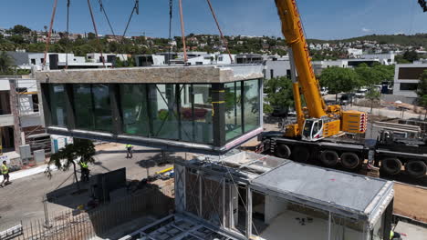 Crane-lifting-modern-modular-housing-unit-into-position-on-construction-site-foundation