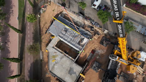 Aerial-view-looking-down-at-industrial-crane-installing-modern-smart-modular-housing-unit-into-foundation