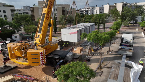Industrial-crane-lifting-modern-modular-housing-property-into-position-on-construction-site