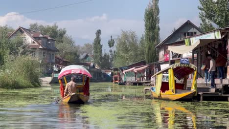 En-Dal-Lake-Kashmiri,-Mucha-Gente-Va-A-Abordar-Un-Bote-Y-Hay-Muchas-Casas-Residenciales-Y-Muchos-árboles-Alrededor.