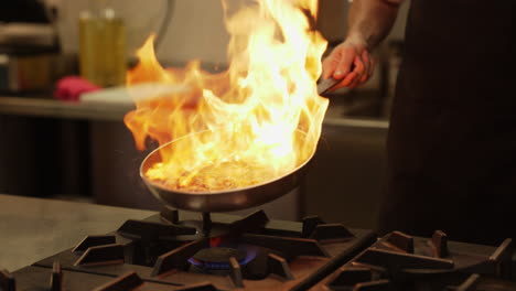 Chef-skillfully-works-with-his-hands,-creating-a-controlled-flame-in-a-hot-saucepan-with-oil