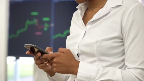 In-the-office-hustle,-a-focused-black-woman-manages-trades-on-her-phone