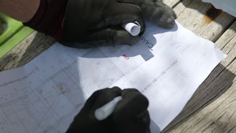 Construction-worker-hands-writing-notes-on-property-blueprint-layout