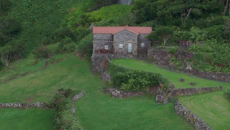 Nahaufnahme-Eines-Hauses-Vor-Einem-Mächtigen-Wasserfall-Auf-Den-Azoren-–-Drohnenaufnahme