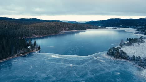 Indre-Fosen,-Condado-De-Trondelag,-Noruega---Un-Lago-Congelado-De-Omundvatnet,-Con-Vegetación-Y-Una-Montaña-Distante-A-La-Vista---Disparo-Aéreo-De-Drones