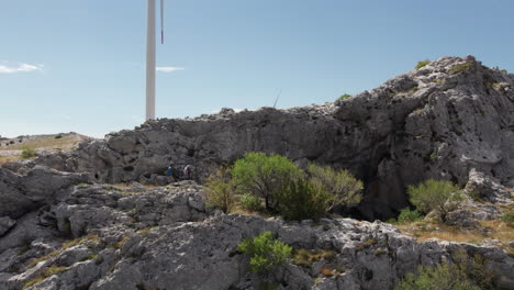 Explorers-going-toward-a-cave-opening-with-wind-turbines-in-the-background