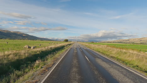 Vehículo-Circulando-Por-La-Autopista-De-Dos-Carriles-Y-Pasa-Por-El-Campo-En-Otago,-Nueva-Zelanda